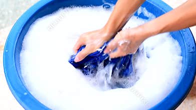 Hand washing clothes in blue basin