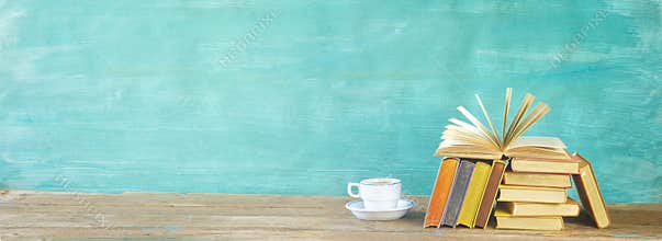 Open Book and stack of multicolored hardback books with a cup of coffee, reading education, literature, panoramic, good copy space