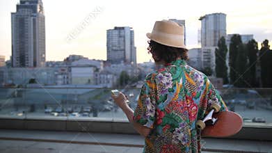 Curly man walking with board scrolling on phone