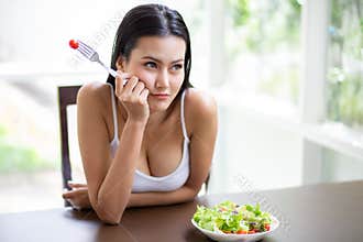 sexy young asian woman in white singlet boring eating fresh organic salad . A beautiful girl have breakfast dislike healthy food