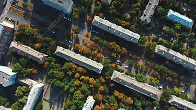 Early autumn in the city, top aerial view. Drone flies over town roofs in the fall. Cars slowly drive through a small