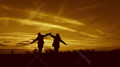 Children dream of flying. Superhero girls running through the meadow against backdrop of a beautiful sky. Children play