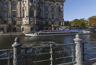 A beautiful cruise boat on the Spree river passes under the Cathedral of Berlin, Germany, on a sunny day