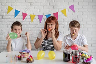 Happy family of mother and two boys blowing up the balloons