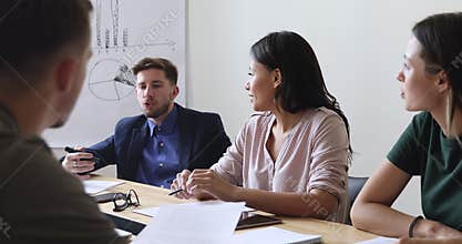 Young multiracial people discussing project details at business meeting.