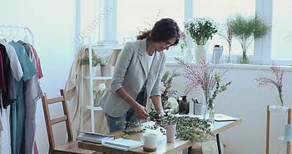 Smiling young designer florist making flower arrangement in creative studio