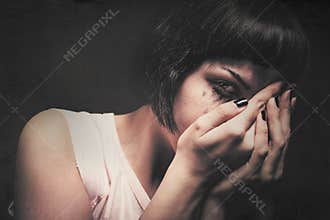 Young woman crying with her hands in her face. Domestic violence. Drained makeup