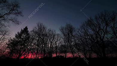 Sunset timelapse in early spring with barren trees and dramatic clouds