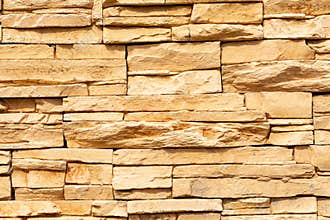 Texture of the yellow surface of a slate stone. Blocks of artificial finishing stone for wall decoration. Rough stone background