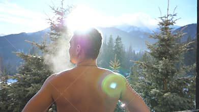 Close up of handsome athletic man standing on balcony and stretching on sunny day. Young guy breathing fresh air and
