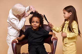 Albino child girl combing curly hair of africanamerican boy isolated