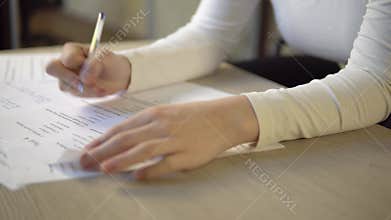 Exam test form on table in class, student taking exams, hand with pen close up