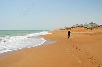 Lonesome hiker walking on sandy coastline