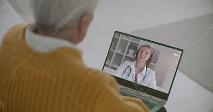 Young female therapist is answering on questions of old person online, elderly man is listening and viewing her on