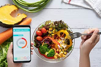 Calories counting , diet , food control and weight loss concept. Calorie counter application on smartphone screen at dining table