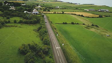 Ireland roadway car driving aerial view: green fields, meadows, farmland, cottages of Antrim County