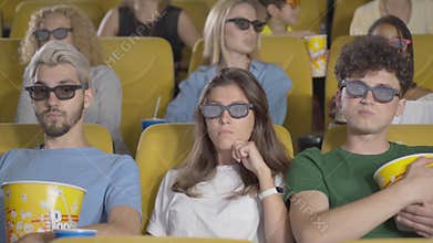 Concentrated cinema visitors in 3d glasses watching film and eating popcorn. Group of people enjoying cinematography in