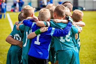 Boys` sports team huddling. Children playing sports in a team. Team sports for kids. Children sports football soccer team