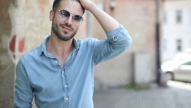 Arrogant young man fixing his shirt`s collar and snapping his fingers