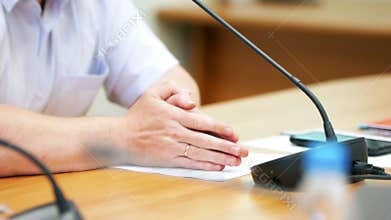 A male politician sitting behind the table - speaking into microphone