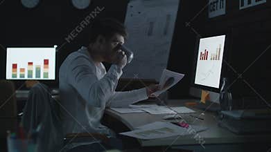 Serious businessman working on computer in night office.