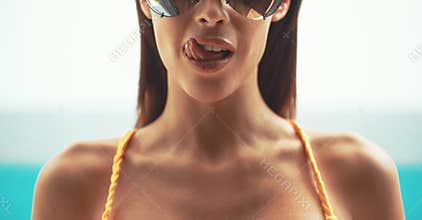 Sexy woman in sunglasses licking lips