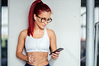 Portrait of an athletic girl working out while listening to music, fitness concept