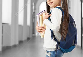 Schoolgirl standing in long school hallway.