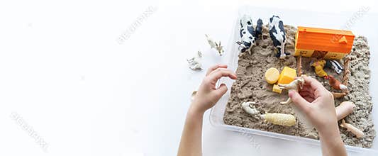 Montessori material. Children`s hands play an animal figure. Kinetic sand. Copy space
