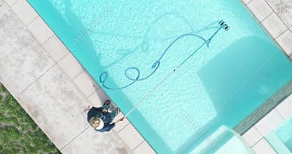 Overhead aerial of woman vacuuming swimming pool