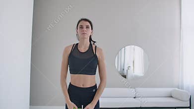 Brunette girl does warm-up and exercises in her apartment in the morning, turns the body blindly and right with arms