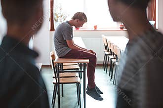 Sad boy sitting alone at school, bullying among children concept