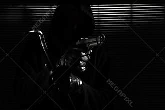 Burglary and robbery. skillful professional masked burglar holding a gun and crowbar and breaking into the house, hand close up on