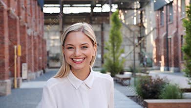 Young beautiful sexy blonde woman in a white shirt spinning in urban street.