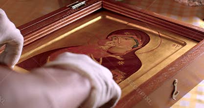 Closeup hands museum worker in gloves hold Christian icon symbol of the Church