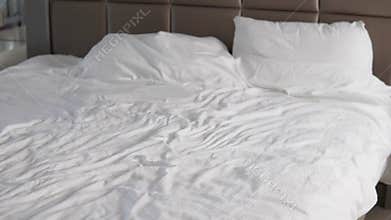 A beautiful little girl cheerfully falls on her parents' bed and laughs