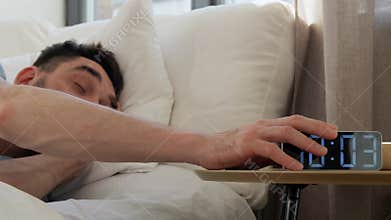 sleeping man delaying alarm clock in morning