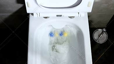 Top view flush water in the toilet. Modern toilet bowl in the interior. Fragrant antimicrobial balls in the bathroom.