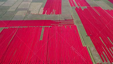 Aerial view of Hundreds of meters of newly dyed, bright red cotton are rolled out to dry in the sun in Narsingdi, Bangladesh.
