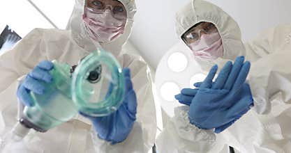 Doctors in hazmat suits prepare anesthesia mask before surgery