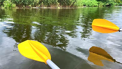 Kayaking on calm river with yellow paddle