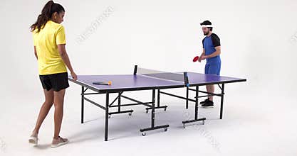 Playing table tennis, man and woman competing in studio setting