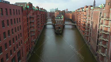 Old red-brick buildings in Speicherstadt along a canal with bridges. Flight through the Warehouse district