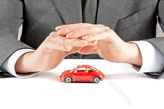 Businessman protect with his hands a red car, concept for insurance, buying, renting, fuel or service and repair costs