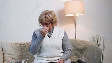 Elderly woman blowing nose while suffering from cold or allergies