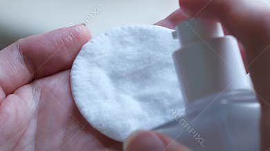 Young woman sprays grooming substance on cotton sponge
