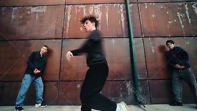 Male dancer executing dynamic hip-hop choreography, performing fluid movements near rusty metal surface with intense