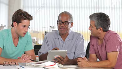 Three Men Using Tablet Computer In Creative Office