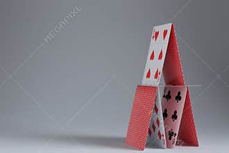 House of playing cards on light grey background. Space for text