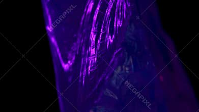 Close-up of irregular natural crystal with vibrant neon colors rotating against abstract background